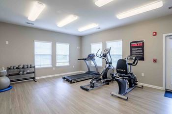 Gym with treadmills, elliptical machines, and a weight rack.